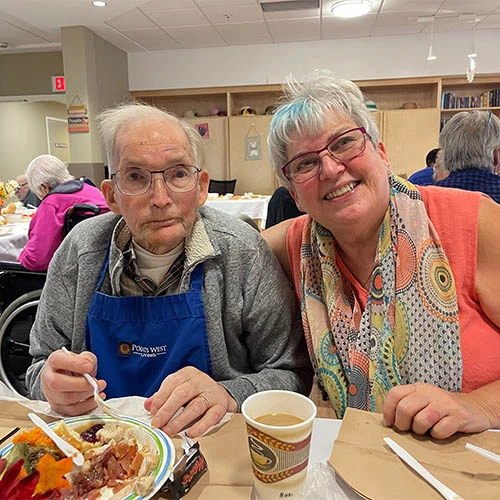 Resident enjoying his Thanksgiving meal with the company of a staff member.