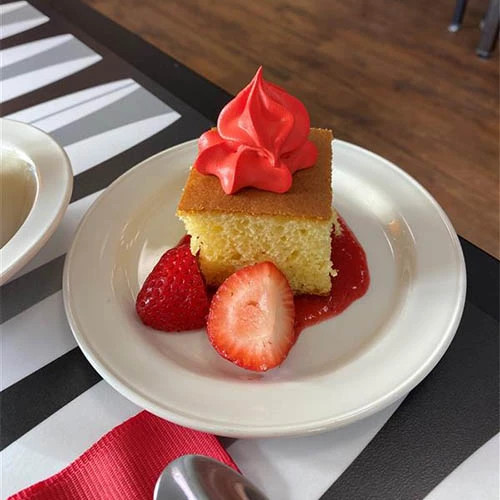 Delicious looking cake with strawberries and red icing on top.