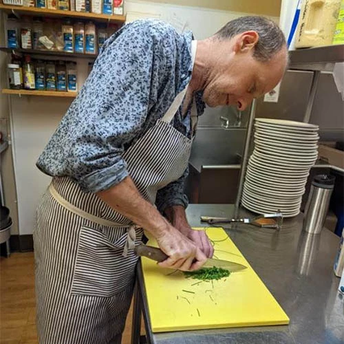 Man cutting on a cutting board in the kitchen.