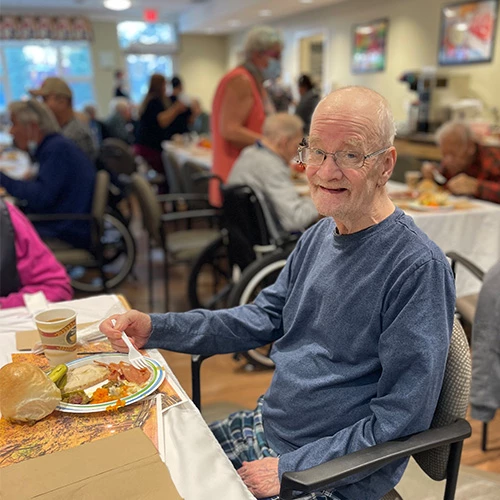 Resident smiling and enjoying a delicious Thanksgiving meal.