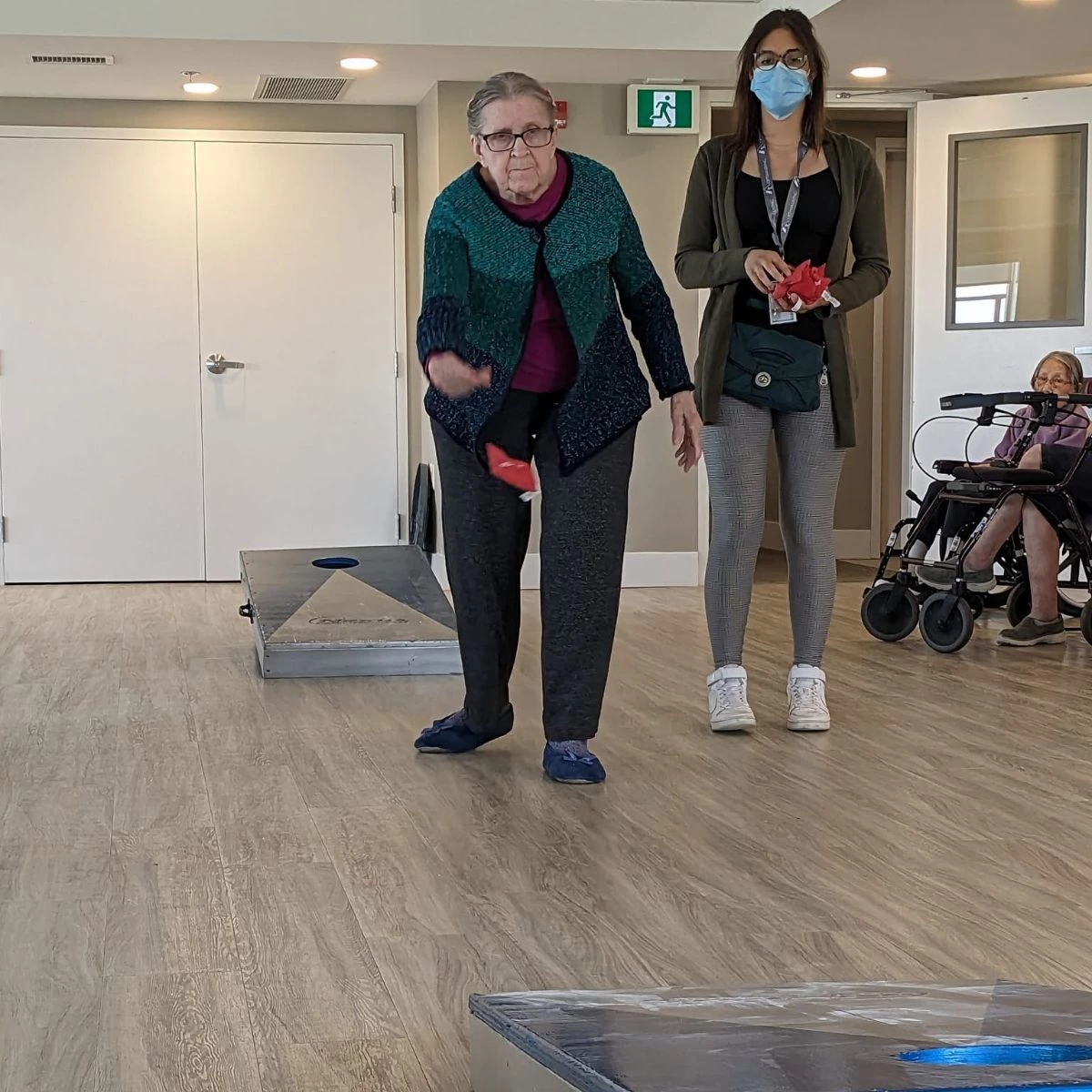A senior resident throwing a beanbag in a game of corn-hole.