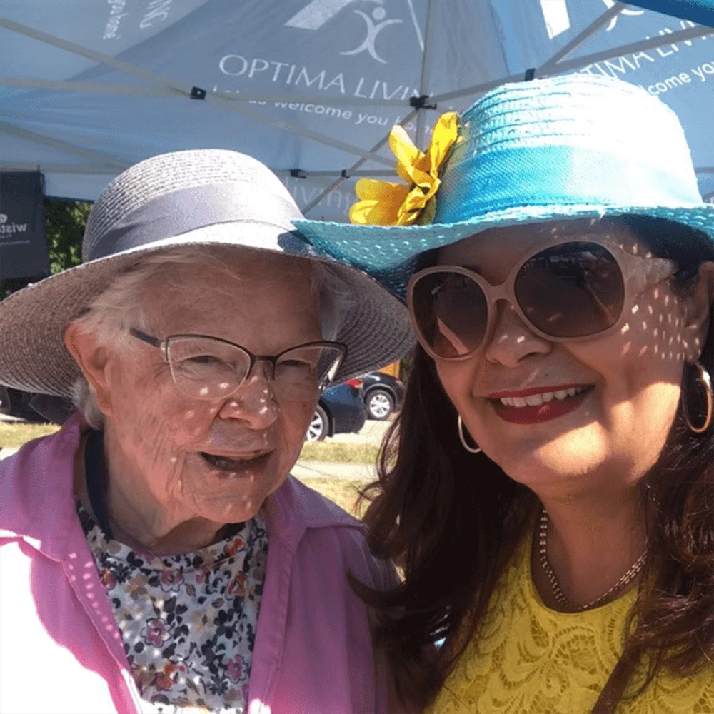 two senior women smiling with bright colored floppy hats