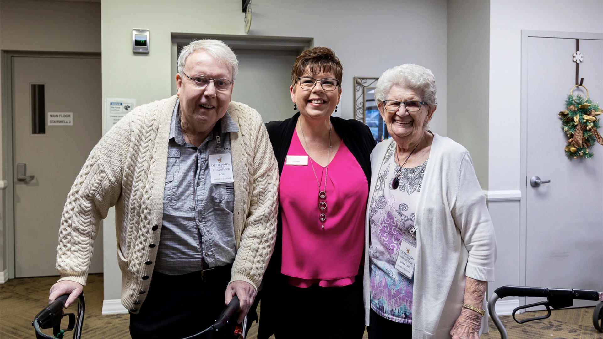 Three people posing for a photo in a hallway.