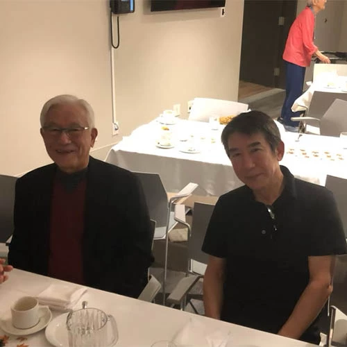 Two men sitting together at table smiling with one another.