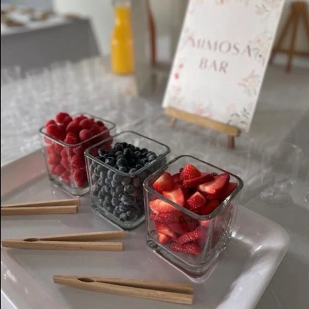 Mimosa bar with fruit in jars. Strawberries, blueberries, and raspberries are in each jar.